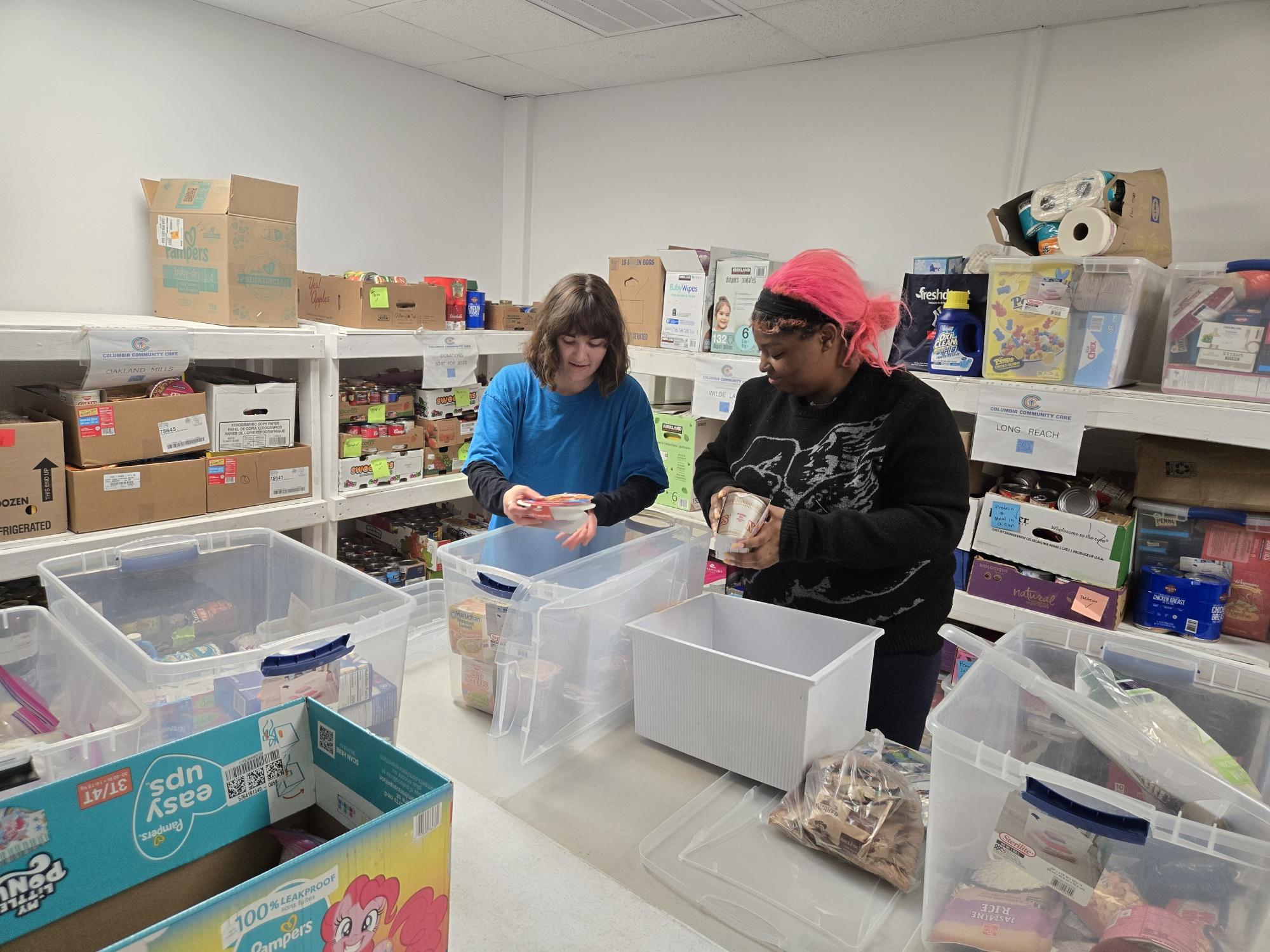 Jocelyn and Sophia restock the shelved at the CCC food pantry