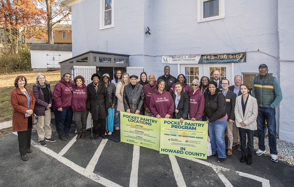 a group poses with a banner announcing the launh of the pocket pantry initiative in howard county maryland