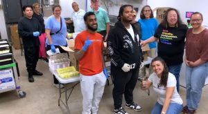 A group of people pose for a picture in the CCC food pantry. David and Zakariya are at the front.